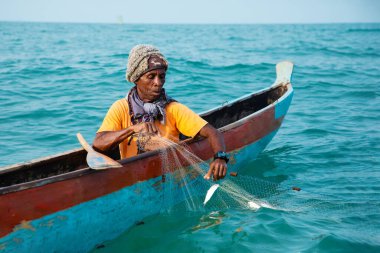 Morondava, Madagaskar. 18 Ekim 2023. Ev yapımı ahşap pirogue teknesindeki kötü niyetli balıkçı ağla balık yakalar. seçici odak, okyanusun yakın görüntüsü