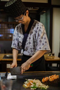 Berlin, Almanya 05. 09 numara. 2019. Teppanyaki şefi bir Japon et lokantasında Teppan 'da yemek pişiriyor. Japon şef ateşli bir gösteri sergiliyor ve alev saçıyor