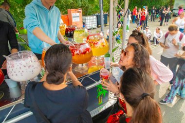 Berlin, Almanya. 22 yaşında. 07 numara. 2023 sıra, çeşitli renkli içeceklerle dolu büyük cam kaseler. Tezgahın arkasında iki kişi. Kokteyl alan çekici kızlar.