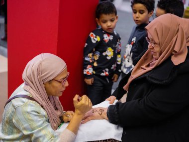 Berlin, Almanya 20.01. 2023 Mehndi ustası kadın eline kına dövmesi çiziyor, mehendi sanat.