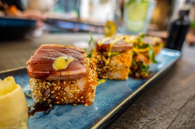 Suşi rulolarının yukarıdan görünüşü. Mavi dikdörtgen seramik tabakta iştah açıcı bir rulo bir restoranda bir masada servis edilir.