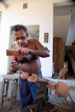 Kolutara, Sri Lanka 09 Şubat 2023. Sri Lanka Geleneksel ağaç ustaları ve zanaatkarları. Ahşaptan el yapımı hediyelik eşya yapmak için küçük bir atölye çalışması. Usta bir Buda heykelciği oyuyor.