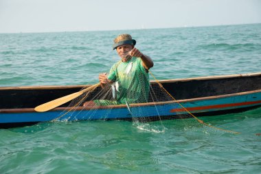 Morondava, Madagaskar. 18 Ekim 2023. Ev yapımı ahşap pirogue teknesindeki kötü niyetli balıkçı ağla balık yakalar. seçici odak, okyanusun yakın görüntüsü