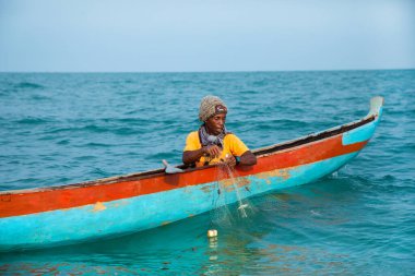 Morondava, Madagaskar. 18 Ekim 2023. Ev yapımı ahşap pirogue teknesindeki kötü niyetli balıkçı ağla balık yakalar. seçici odak, okyanusun yakın görüntüsü