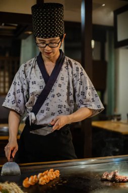 Berlin, Almanya 05. 09 numara. 2019. Teppanyaki şefi bir Japon et lokantasında Teppan 'da yemek pişiriyor. Japon şef ateşli bir gösteri sergiliyor ve alev saçıyor