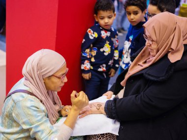 Berlin, Almanya 20.01. 2023 Mehndi ustası kadın eline kına dövmesi çiziyor, mehendi sanat.