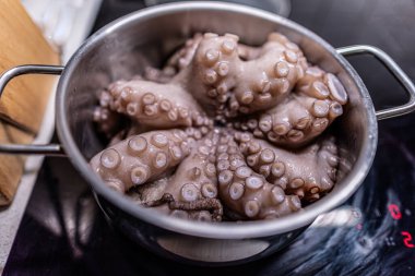 Pişirme işlemi sırasında hafif mutfakta, modern siyah indüksiyon fırınında haşlanmış çiğ ahtapot..