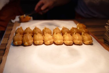 Pasta kağıdının üzerindeki hamur işlerinden yapılmış şekiller. Linzer Noel kurabiyelerinin hazırlanması. Tanımlanamayan kadın elleri cımbızla taze kurabiye taşıyor.