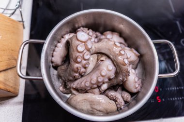 Pişirme işlemi sırasında hafif mutfakta, modern siyah indüksiyon fırınında haşlanmış çiğ ahtapot..