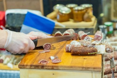 Tanımlanamayan kadın elleri bir mağazanın tezgahında bir parça salam kesti ve denemesi için alıcıya verdi. Görünür yüz yok