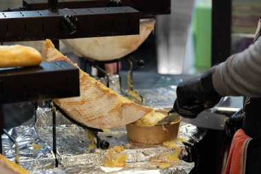 Lezzetli bir raclette peyniri son teknoloji ürünü ısıtıldı. Bu lezzetli Avrupa lezzetini bekleyen, ağzı sulanan müşterilere servis edildiğinde erimiş durumdadır. Geleneksel Fransız fast food