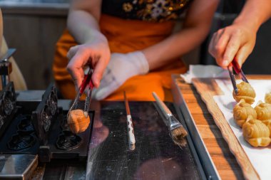 Pasta kağıdının üzerindeki hamur işlerinden yapılmış şekiller. Linzer Noel kurabiyelerinin hazırlanması. Tanımlanamayan kadın elleri cımbızla taze kurabiye taşıyor.
