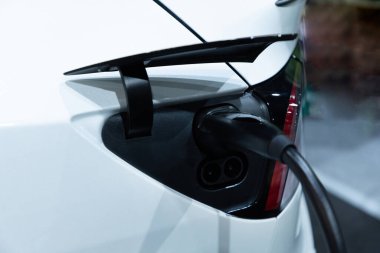 Kapalı EV şarj kolu fişe takıldı veya elektrikli arabaya bağlandı, EV araba aküsünü temiz çevre için sıfır CO2 emisyonu ile alternatif ve sürdürülebilir enerjiyle şarj etti. Çevre dostu