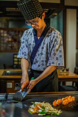 Berlin, Almanya 05. 09 numara. 2019. Teppanyaki şefi bir Japon et lokantasında Teppan 'da yemek pişiriyor. Japon şef ateşli bir gösteri sergiliyor ve alev saçıyor