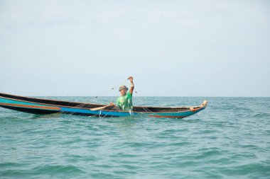 Morondava, Madagaskar. 18 Ekim 2023. Ev yapımı ahşap pirogue teknesindeki kötü niyetli balıkçı ağla balık yakalar. seçici odak, okyanusun yakın görüntüsü
