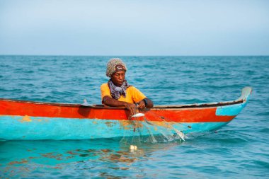 Morondava, Madagaskar. 18 Ekim 2023. Ev yapımı ahşap pirogue teknesindeki kötü niyetli balıkçı ağla balık yakalar. seçici odak, okyanusun yakın görüntüsü