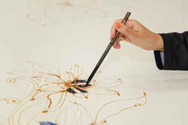 Kuala Lumpur, Malezya. 04.08.2024. Malezya Batik Kumaşındaki Fırça Boyalı El adlı kadın..