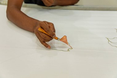 Malezya Batik Kumaşı 'nda Batik' i boyayan özel balmumu alet fırçasıyla yakın plan adamı El.