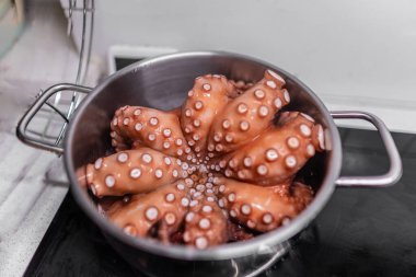 Haşlanmış kırmızı ahtapot tavadan çıkarılır. Bir ahtapotun tüm leşi. Mutfakta sıcak su var. Tanımlanamayan fotoğraf. Boşluğu kopyala.