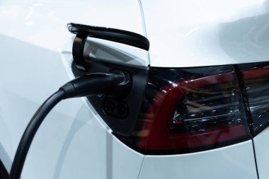 Kapalı EV şarj kolu fişe takıldı veya elektrikli arabaya bağlandı, EV araba aküsünü temiz çevre için sıfır CO2 emisyonu ile alternatif ve sürdürülebilir enerjiyle şarj etti. Çevre dostu
