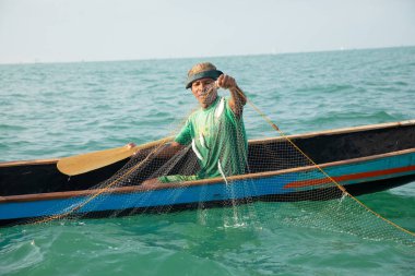 Morondava, Madagaskar. 18 Ekim 2023. Ev yapımı ahşap pirogue teknesindeki kötü niyetli balıkçı ağla balık yakalar. seçici odak, okyanusun yakın görüntüsü