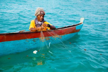Morondava, Madagaskar. 18 Ekim 2023. Ev yapımı ahşap pirogue teknesindeki kötü niyetli balıkçı ağla balık yakalar. seçici odak, okyanusun yakın görüntüsü