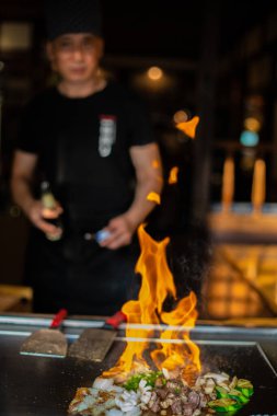 Berlin, Almanya 08. 16 yaşında. 2023. Teppanyaki şefi bir Japon et lokantasında Teppan 'da yemek pişiriyor. Japon aşçı ateşli bir gösteri sergiliyor.