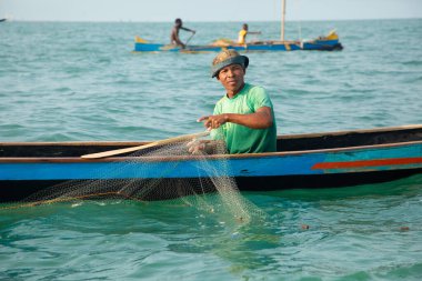 Morondava, Madagaskar. 18 Ekim 2023. Ev yapımı ahşap pirogue teknesindeki kötü niyetli balıkçı ağla balık yakalar. seçici odak, okyanusun yakın görüntüsü