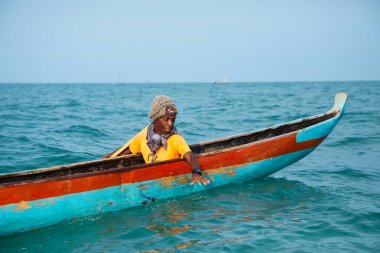 Morondava, Madagaskar. 18 Ekim 2023. Ev yapımı ahşap pirogue teknesindeki kötü niyetli balıkçı ağla balık yakalar. seçici odak, okyanusun yakın görüntüsü