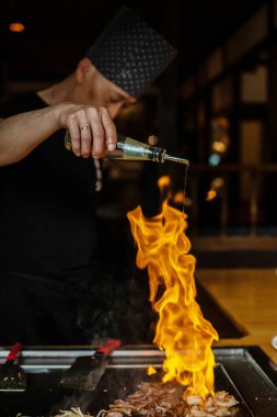 Berlin, Almanya 08. 16 yaşında. 2023. Teppanyaki şefi bir Japon et lokantasında Teppan 'da yemek pişiriyor. Japon şef ateşli bir gösteri sergiliyor ve alev saçıyor