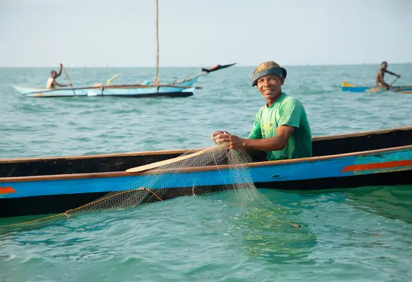 Morondava, Madagaskar. 18 Ekim 2023. Ev yapımı ahşap pirogue teknesindeki kötü niyetli balıkçı ağla balık yakalar. seçici odak, okyanusun yakın görüntüsü