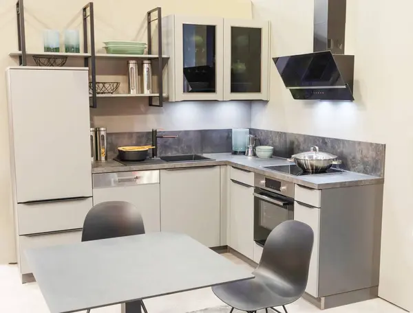 Yemek masası paslanmaz aletleri olan modern bir çiftlik evi mutfağı. Modern iç mekan, açık gri tonlarda yeni mutfak mobilyaları.
