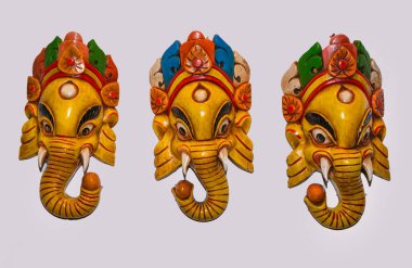 Traditional Hindu Masks. traditional Nepalese elephant masks in Hindu style isolated torn on a white background hanging on a white wall clipart