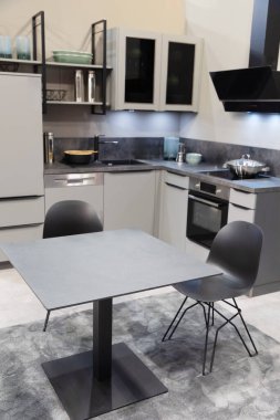 Yemek masası paslanmaz aletleri olan modern bir çiftlik evi mutfağı. Modern iç mekan, açık gri tonlarda yeni mutfak mobilyaları.