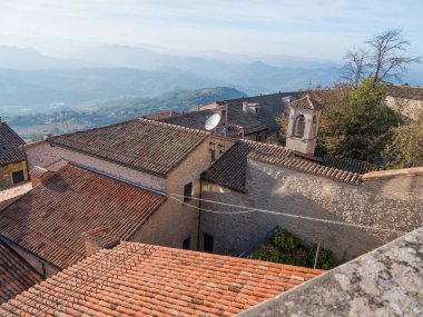San Marino Cumhuriyeti. Dağdaki 31.10.2022 antik kale. Dar sokaklar turist, restoran ve hediyelik eşya dükkanlarıyla dolu. Aşağıda gün batımında güzel bir dağ manzarası var.