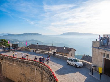 San Marino Cumhuriyeti. Dağdaki 31.10.2022 antik kale. Dar sokaklar turist, restoran ve hediyelik eşya dükkanlarıyla dolu. Aşağıda gün batımında güzel bir dağ manzarası var.