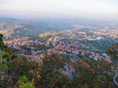 San Marino Cumhuriyeti. Dağdaki 31.10.2022 antik kale. Dar sokaklar turist, restoran ve hediyelik eşya dükkanlarıyla dolu. Aşağıda gün batımında güzel bir dağ manzarası var.