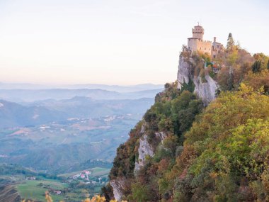 San Marino Cumhuriyeti. Dağdaki 31.10.2022 antik kale. Dar sokaklar turist, restoran ve hediyelik eşya dükkanlarıyla dolu. Aşağıda gün batımında güzel bir dağ manzarası var.