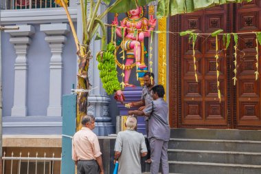 Colombo, Sri Lanka 03.02.2023, birçok renkli ruhani figürle eski bir Sri Lanka tapınağı. İnsanlar tapınak kapısından yiyecek alıyor.