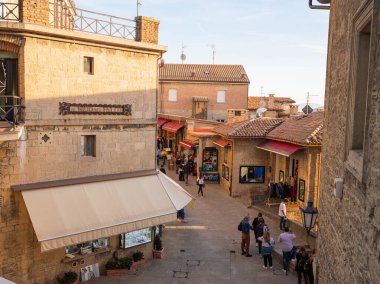 San Marino Cumhuriyeti. Dağdaki 31.10.2022 antik kale. Dar sokaklar turist, restoran ve hediyelik eşya dükkanlarıyla dolu. Aşağıda gün batımında güzel bir dağ manzarası var.