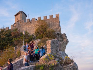 San Marino Cumhuriyeti. Dağdaki 31.10.2022 antik kale. Dar sokaklar turist, restoran ve hediyelik eşya dükkanlarıyla dolu. Aşağıda gün batımında güzel bir dağ manzarası var.