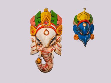 Traditional Hindu Masks. traditional Nepalese elephant masks in Hindu style isolated torn on a white background hanging on a white wall clipart