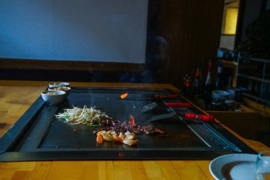 Şefin elleri teppanyaki yerine spatula ile. Sebze pişirmek et ve deniz ürünleri sıcak hibachi ızgara masasında. Geleneksel Japonca. Teppan gösterisi. Dünya mutfağı kavramı