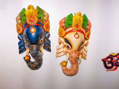 Traditional Hindu Masks. traditional Nepalese elephant masks in Hindu style isolated torn on a white background hanging on a white wall clipart