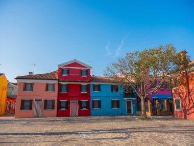 Burano, Venedik, İtalya 29.10.2022. Burano adası, kanalların farklı taraflarındaki parlak renkli evler ve sudaki renkli yansımalar. gün batımı