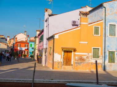 Burano, Venedik, İtalya 29.10.2022. Burano adası, Venedik bölgesi. Kanalların farklı taraflarındaki parlak renkli evler ve suda renkli yansımalar. Eski binalarla dolu dar sokaklar
