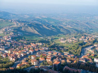 San Marino Cumhuriyeti. Dağdaki 31.10.2022 antik kale. Dar sokaklar turist, restoran ve hediyelik eşya dükkanlarıyla dolu. Aşağıda gün batımında güzel bir dağ manzarası var.