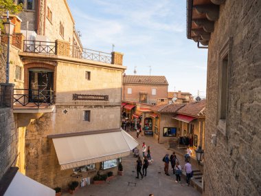 San Marino Cumhuriyeti. Dağdaki 31.10.2022 antik kale. Dar sokaklar turist, restoran ve hediyelik eşya dükkanlarıyla dolu. Aşağıda gün batımında güzel bir dağ manzarası var.