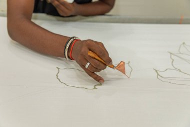 Malezya Batik Kumaşı 'nda Batik' i boyayan özel balmumu alet fırçasıyla yakın plan adamı El.