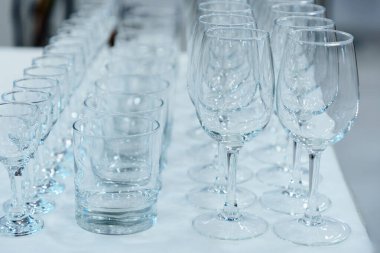 Alkol için saydam bardaklar beyaz masanın üzerinde duruyor..